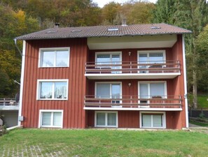 Un immeuble à deux étages, à la façade rouge, doté de nombreuses fenêtres et de balcons.