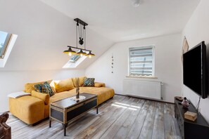 Une pièce de style loft avec un canapé, une table basse, un téléviseur et une lucarne.
