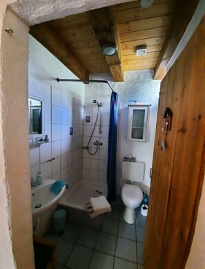 Ein kleines Badezimmer mit Dusche, Toilette und Waschbecken.