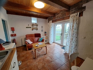 Un salon chaleureux avec un canapé en cuir, une table basse en bois et un coin repas comprenant une table et des chaises blanches.