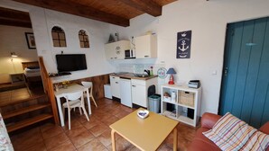 Un ambiente compatto con angolo cottura, zona pranzo e divano.