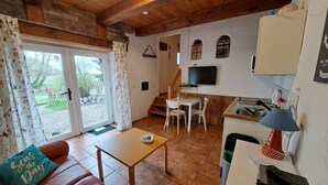 Un accogliente soggiorno con divano, un tavolino, una TV e un angolo cottura con lavello e pensili.