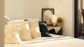 Ein Hotelzimmer mit einem großen Bett, einem Schreibtisch mit Stuhl, einer Lampe und einem gerahmten Bild an der Wand.