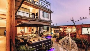 A multi-story building with a rooftop bar, outdoor seating, and a hot tub. - Long Sunshine (Dali City)