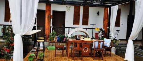 Un patio al aire libre con cubierta de madera, mesa de comedor, sillas y macetas con plantas.