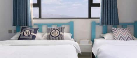 A hotel room with two beds, each with a different pillow design, a nightstand, and a view of the sky and mountains.