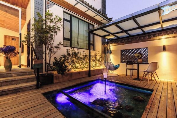 A wooden deck with a hot tub, surrounded by plants and a covered seating area. - Long Sunshine (Dali City)