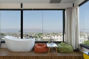 A modern room with a large window, a white bathtub, and two bean bags. - Long Sunshine (Dali City)