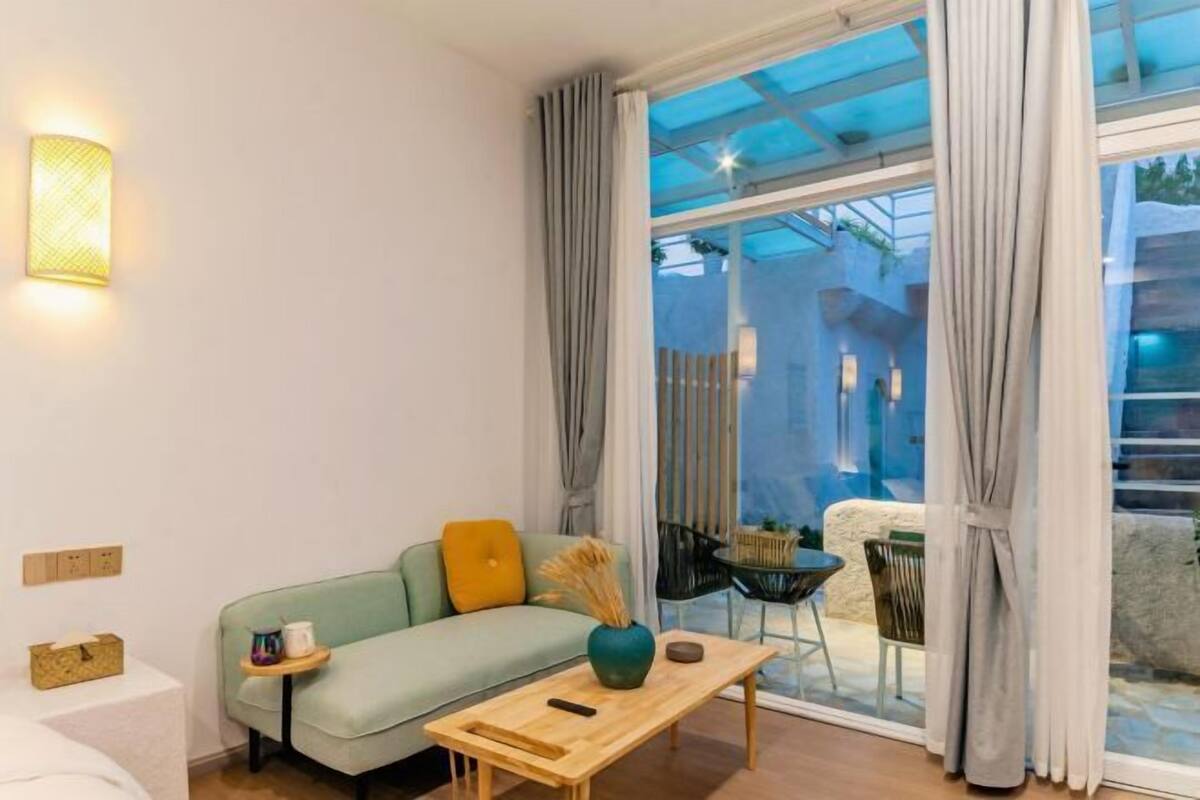 Un salon moderne avec un canapé, une table basse et une vue dégagée grâce à de grandes fenêtres.