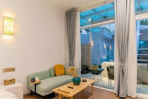 Una sala de estar moderna con un sofá, una mesa de centro y vistas a través de amplios ventanales.