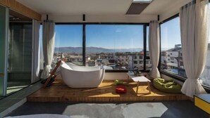 A modern room with a large window, a bathtub, a wooden platform, and a view of the city. - Long Sunshine (Dali City)