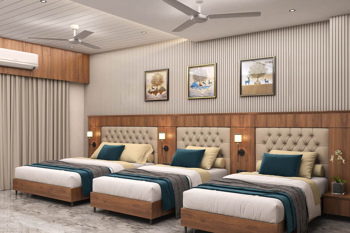 Ein Hotelzimmer mit drei Betten, einem Deckenventilator, Wandklimaanlage und gerahmten Kunstwerken.
