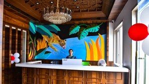 Un mostrador de recepción con un mural de leopardo, paneles de madera y una araña.