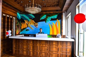 Un mostrador de recepción con un mural de leopardo, paneles de madera y una araña.