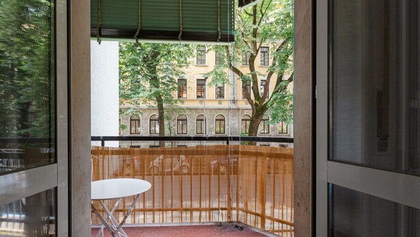 Ein Balkon mit Blick auf ein Gebäude, einem weißen Tisch und einem roten Backsteinboden.