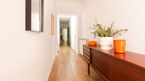 Ein Flur mit Holzboden, einem Holzschrank, einem Spiegel und einem Blumentopf.