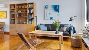 Una sala de estar moderna con piso de madera, un sofá, una mesa de centro, una estantería y un cuadro en la pared.