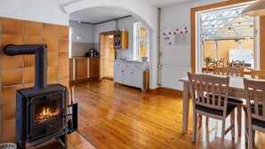 Una cocina acogedora con estufa de leña, armarios de madera y un comedor con mesa y sillas.