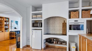 Una cocina moderna con armarios blancos, horno empotrado, microondas y salpicadero de azulejos.