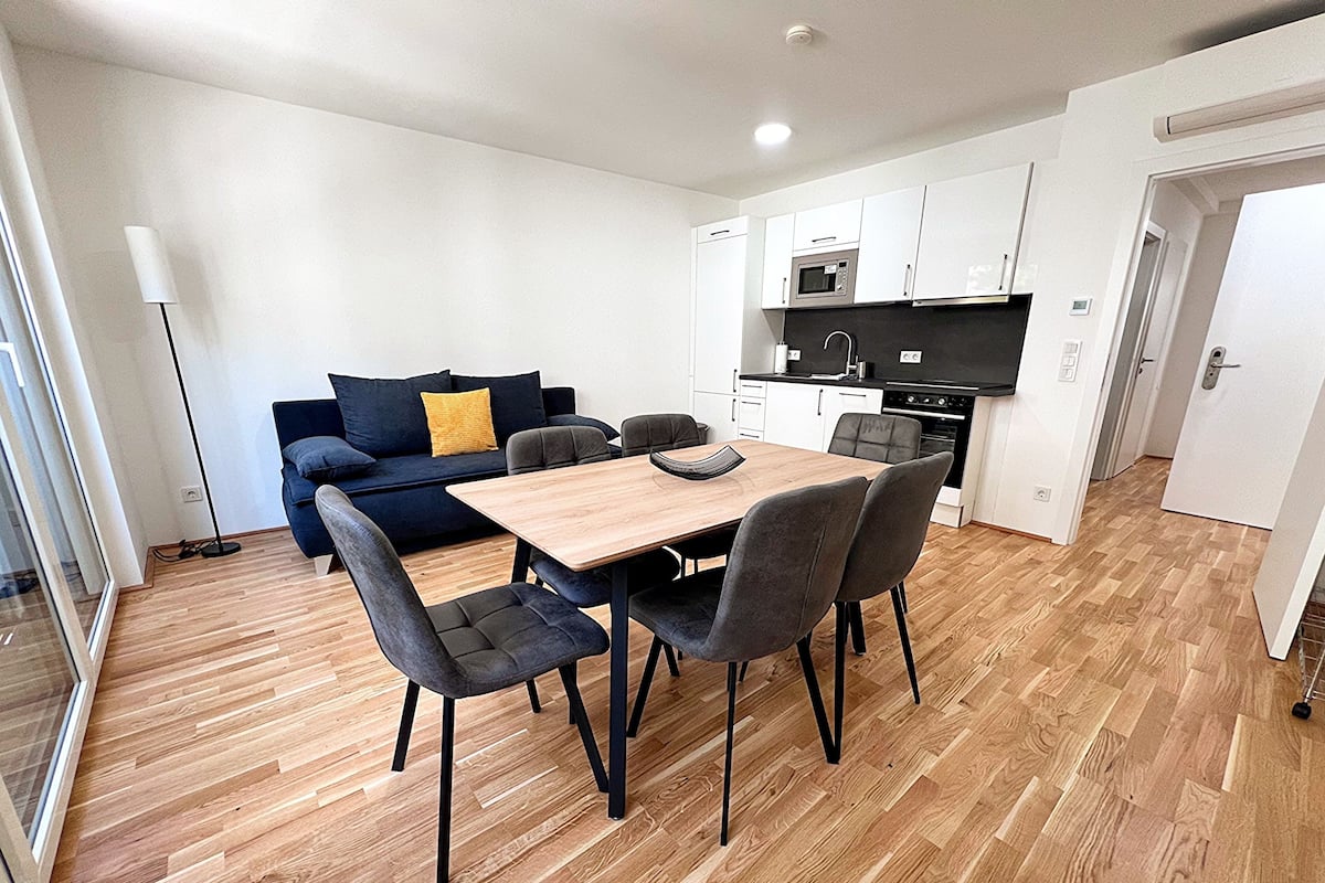 A modern apartment with a dining area, kitchen, and living space.
