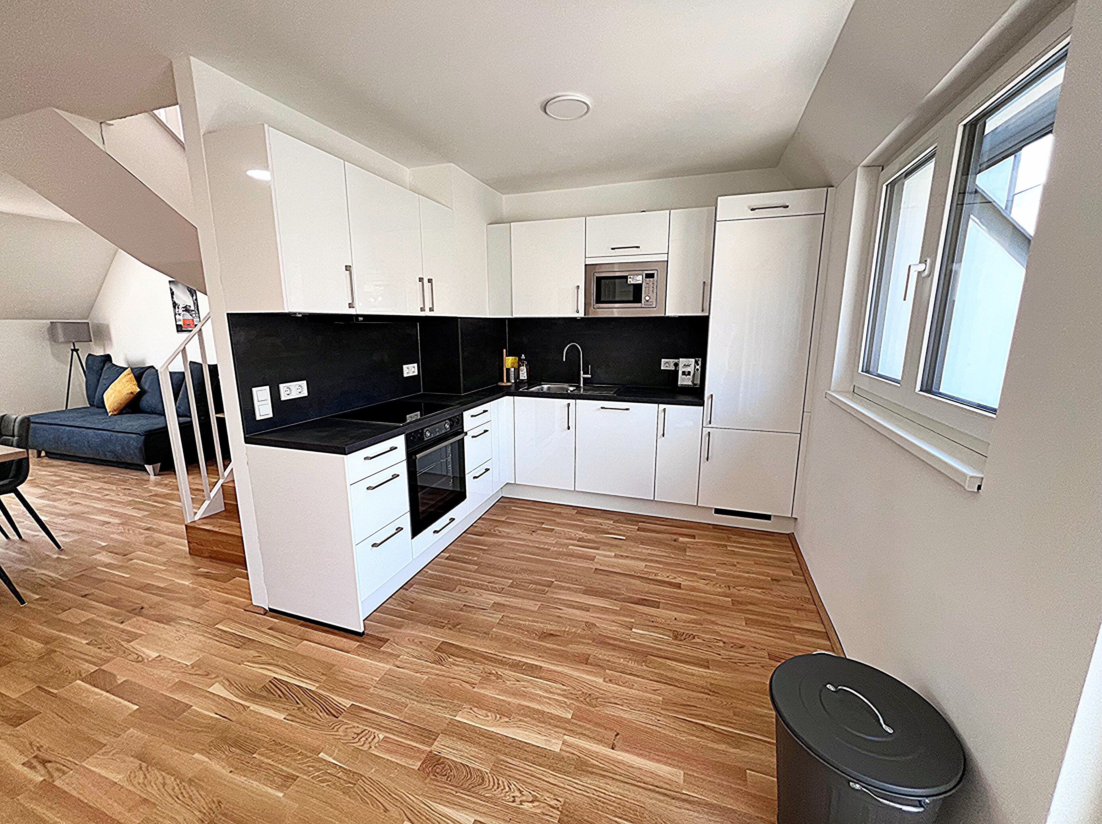 A compact kitchen with white cabinets, a black countertop, and a microwave.