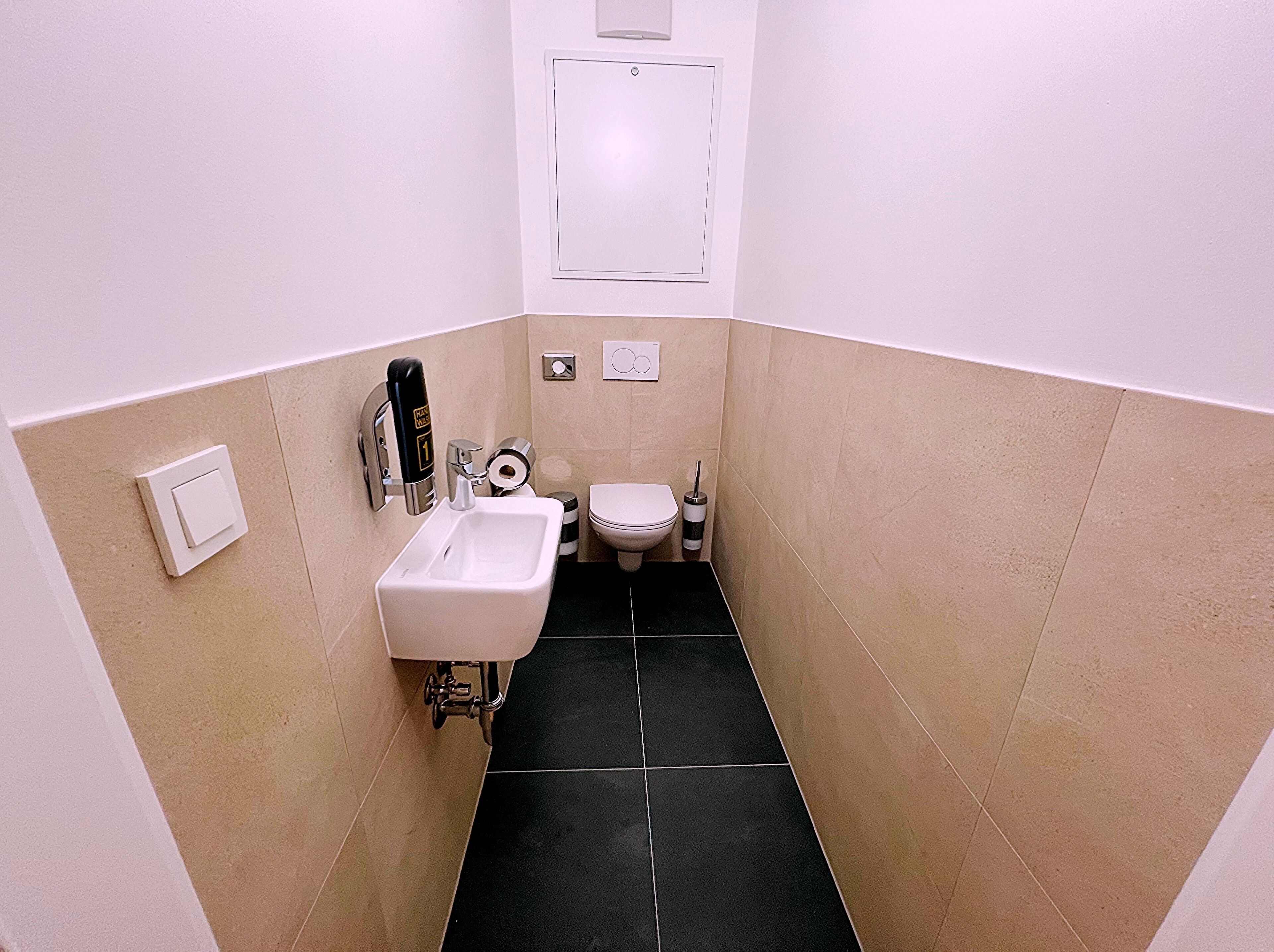 A small bathroom with a sink, toilet, and a towel dispenser.