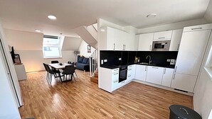 Une cuisine moderne avec des meubles blancs, un plan de travail noir et un plancher en bois.