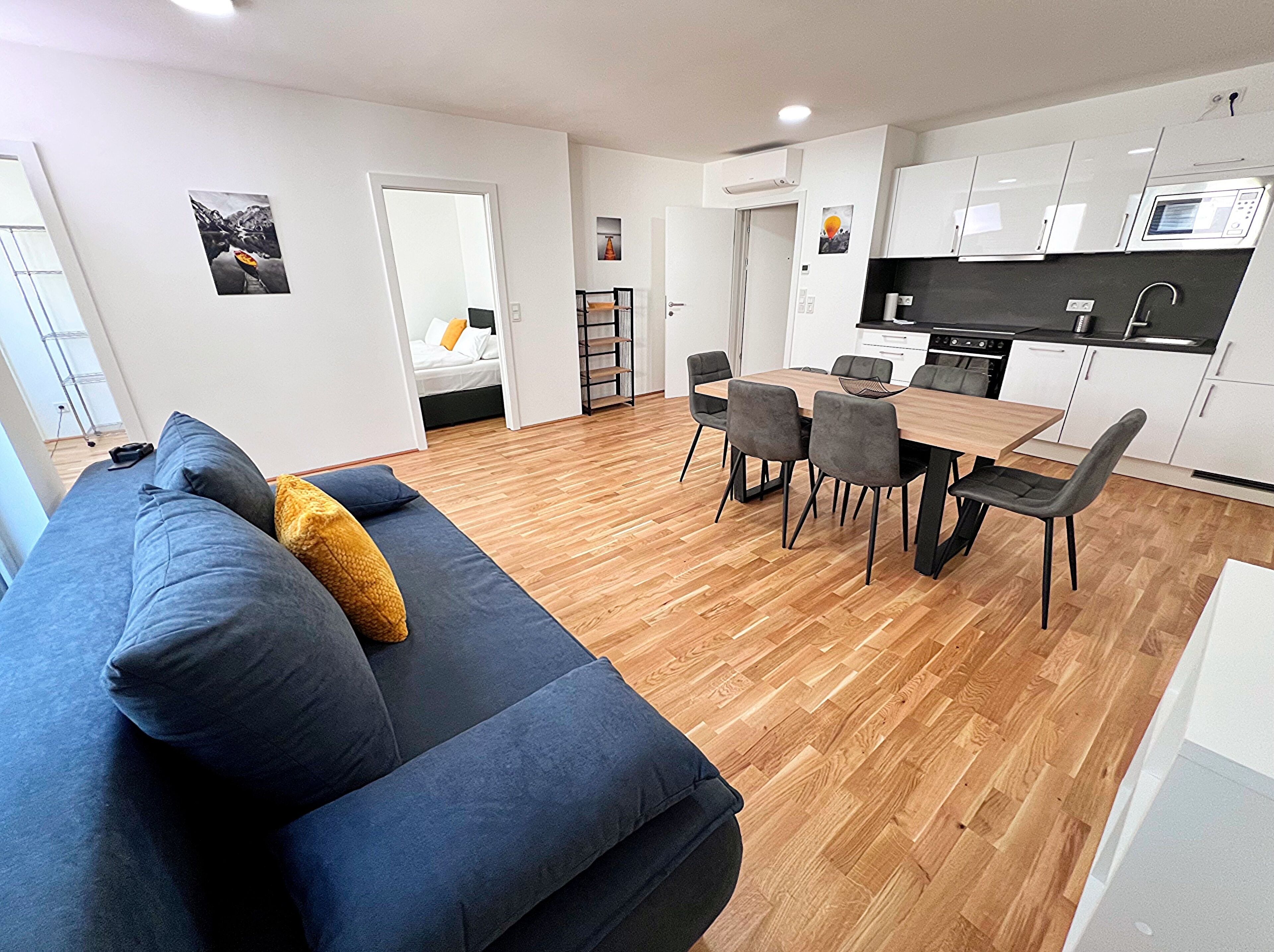 A modern apartment with a living room, dining area, and kitchen.