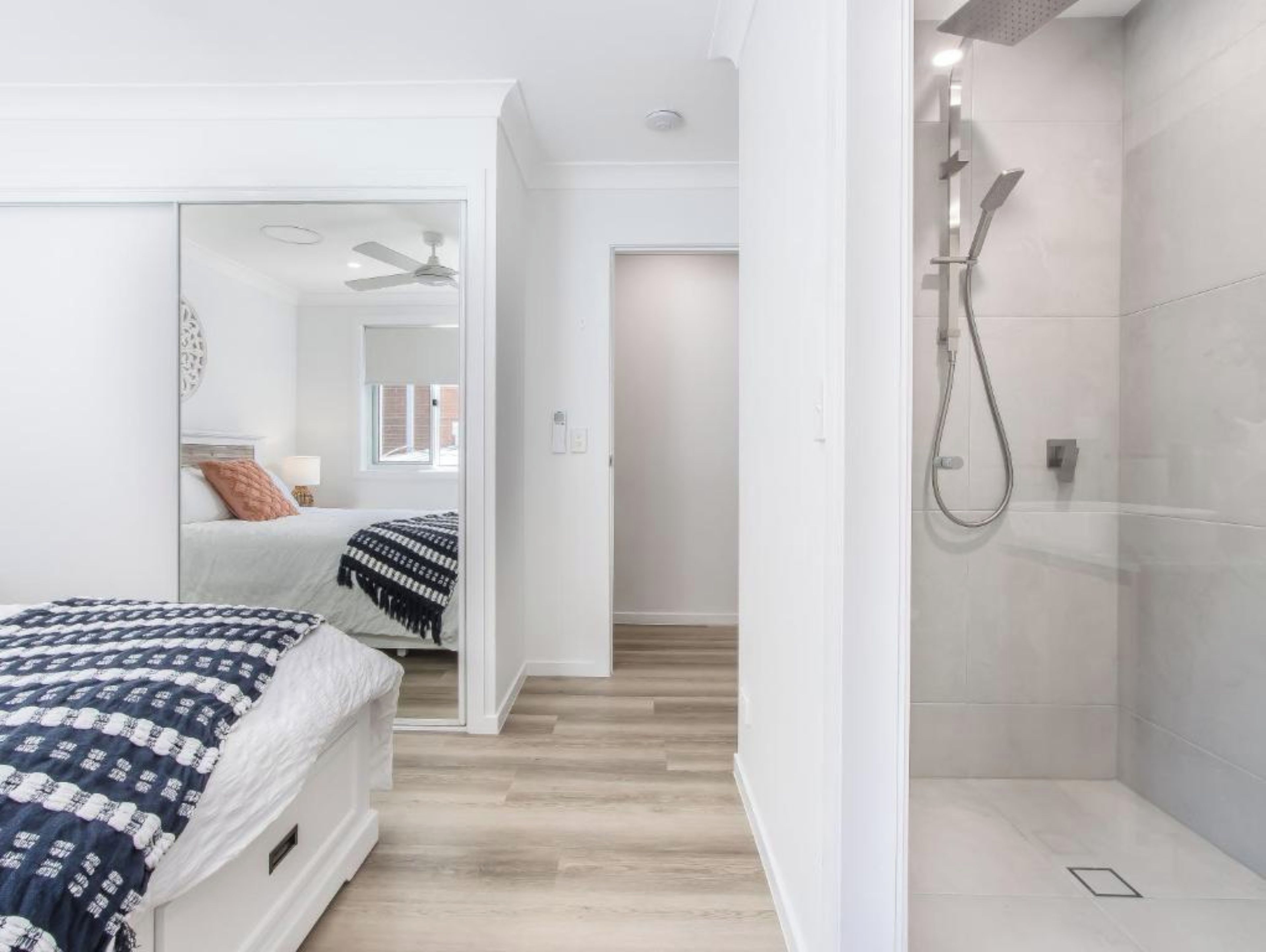 A bedroom with a bed, a walk-in closet, and a shower area.