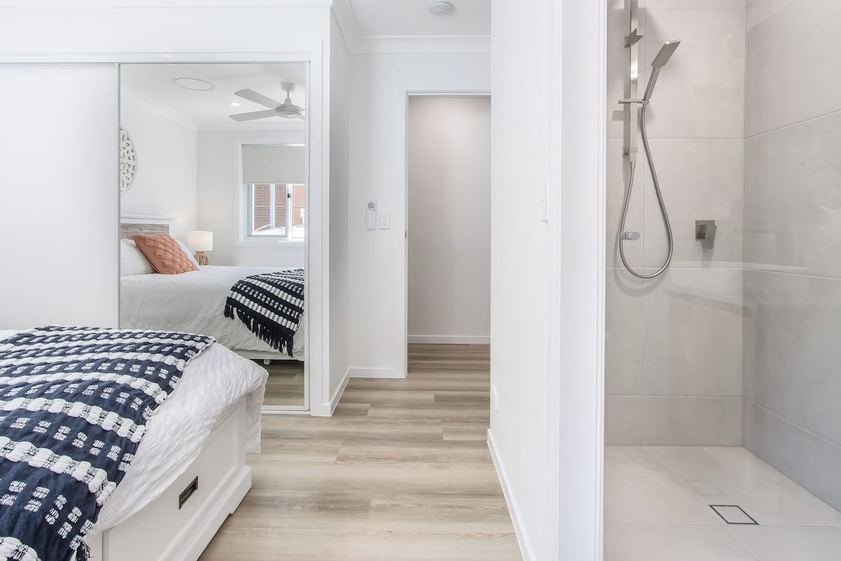 Een moderne slaapkamer met een groot bed, een inloopkast en een douche.