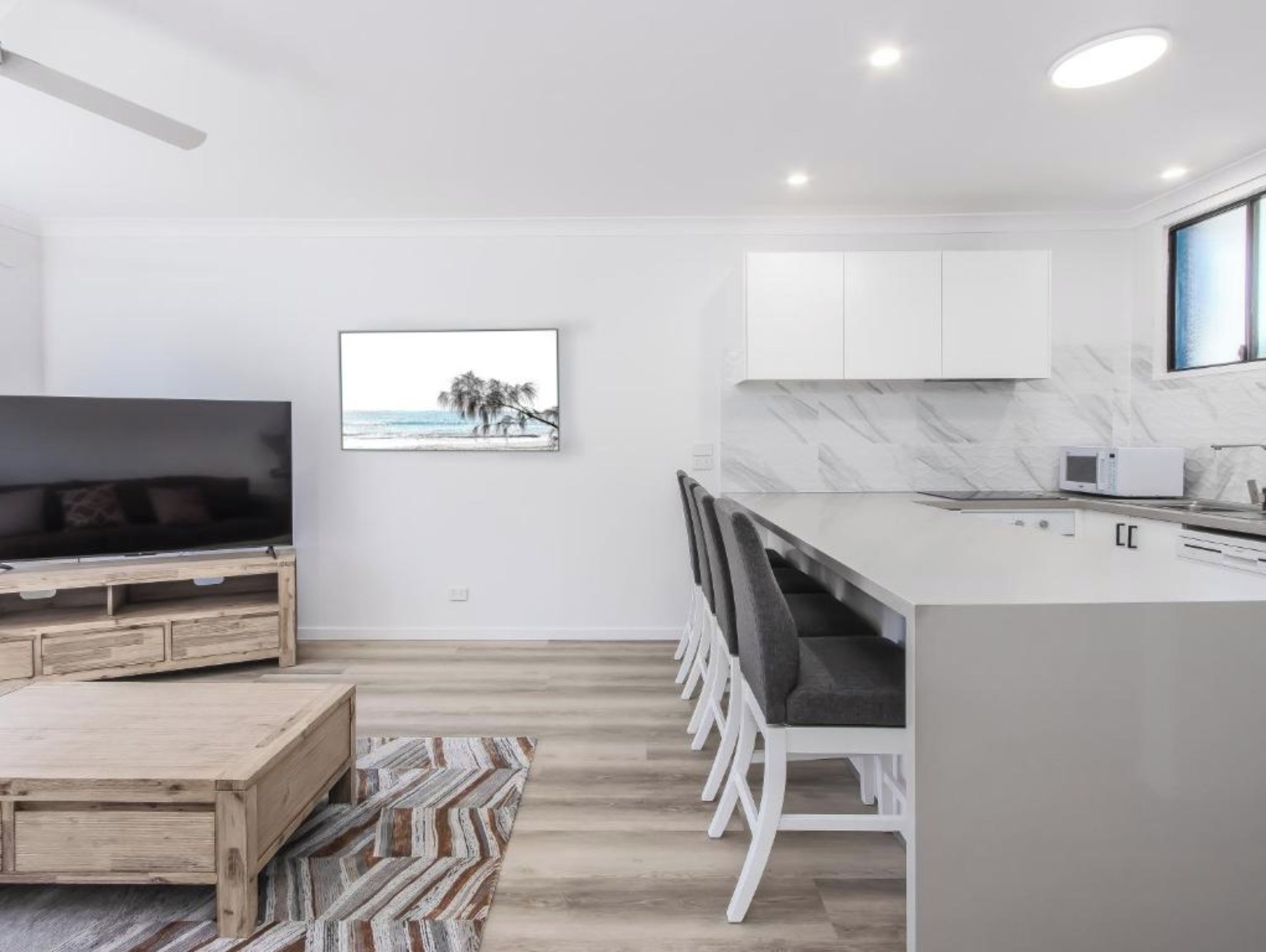 A modern kitchen with white cabinets, a marble backsplash, and a built-in microwave.