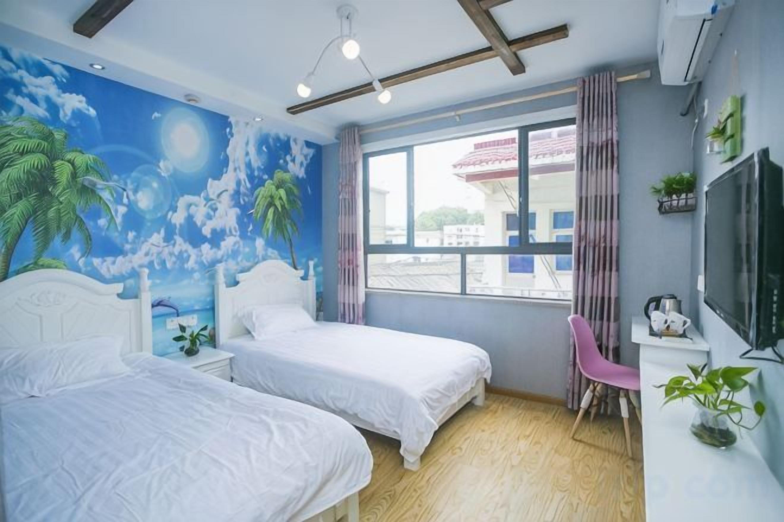 A room with two beds, a desk, a TV, and a window with a view of buildings.