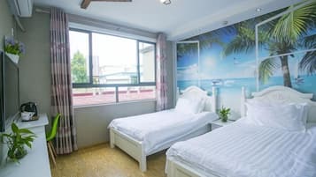 A bedroom with two beds, a window with curtains, a wall mural, and a small bedside table with a plant.
