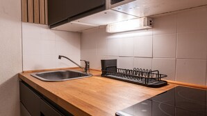 A kitchen with a stainless steel sink, wooden countertop, and a black dish rack. - Lovely 4 pers studio at the foot of the pistes (Morillon)