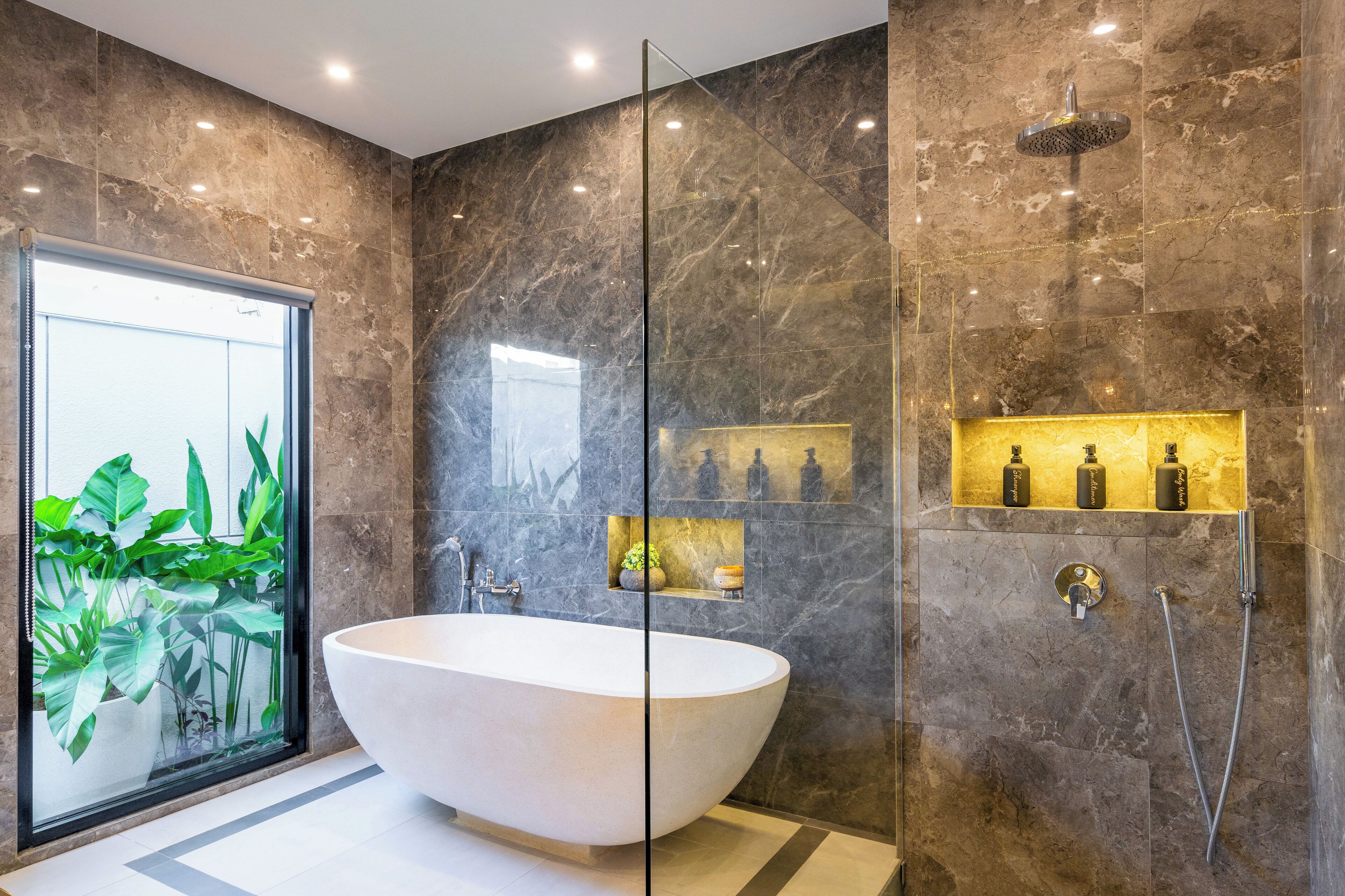 A modern bathroom with a freestanding bathtub, a glass shower enclosure, and a marble wall.