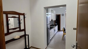 Un pasillo con estante de madera, un espejo y una puerta que da a una zona de cocina.