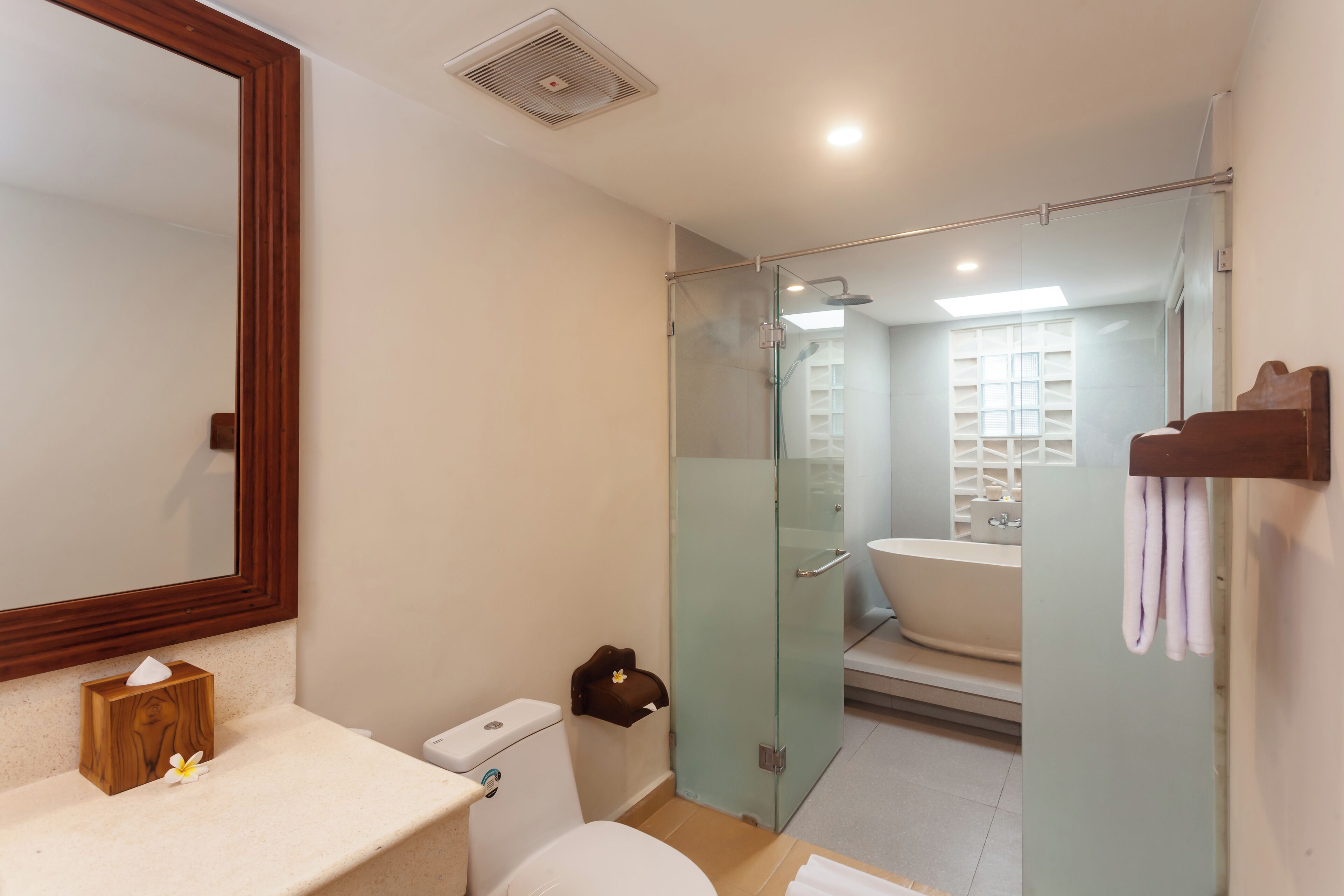 A modern bathroom with a glass-enclosed shower, a white sink, and a wooden vanity.