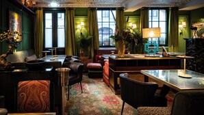 A cozy hotel lobby with a patterned carpet, comfortable seating, and a fireplace.