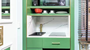 A compact kitchenette with a microwave, sink, and storage cabinets.