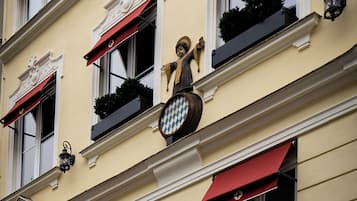 Un hotel con toldos rojos, un cartel con una figura y elementos decorativos en la fachada.