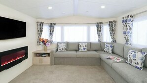 A living room with a sofa, a flat-screen TV, a fireplace, and patterned curtains.