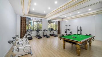 A room with exercise equipment, a pool table, and large windows.