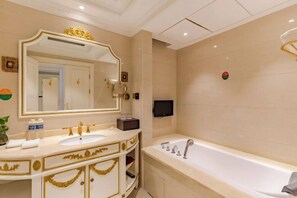 A luxurious bathroom with a large mirror, a bathtub, and a vanity with gold detailing.