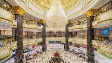 A grand lobby with a large chandelier, marble floors, and ornate columns.