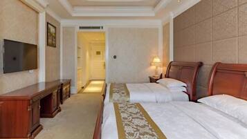 A hotel room with two beds, a TV, a desk, and a lamp.