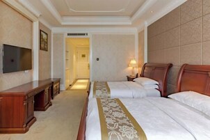 Habitación de hotel con dos camas, televisión, escritorio y lámpara.