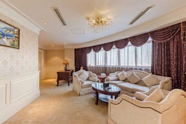 A spacious living room with a large sofa set, a coffee table, and a chandelier.