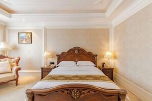 A classic four-poster bed with ornate woodwork, a pair of nightstands with lamps, and a framed picture on the wall.