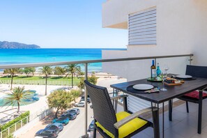 A balcony with a table set for two, overlooking a beach and ocean. - Nice apartment in Cala Millor (Cala Millor)