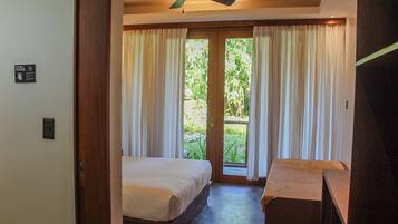 A bedroom with a bed, a desk, and a ceiling fan.